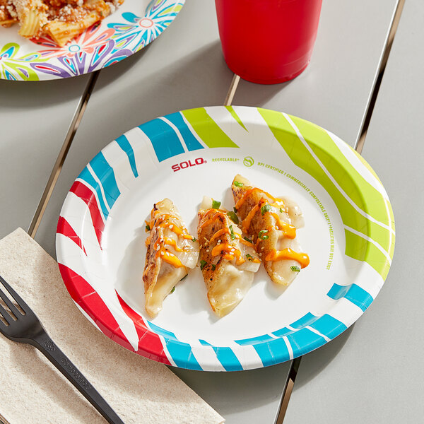 A Solo AnyDay paper plate with food on it and a drink on a table.