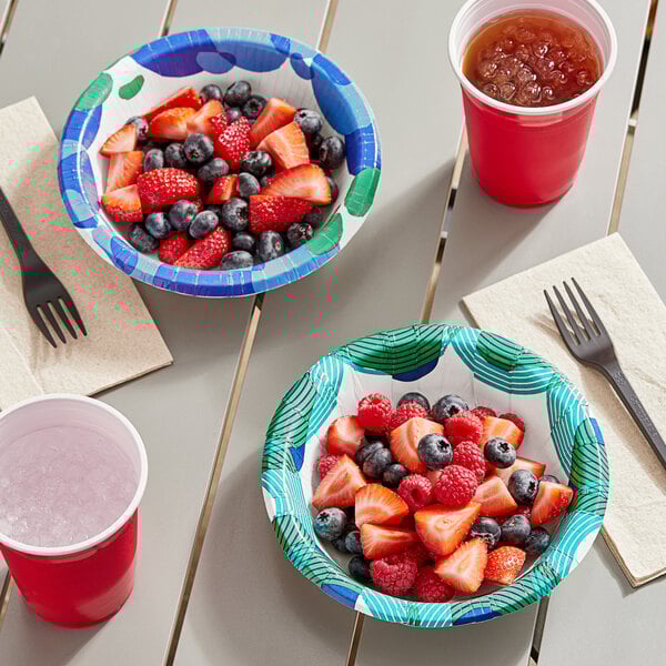 A table with Solo sea glass paper bowls filled with blueberries and strawberries and a cup of water.