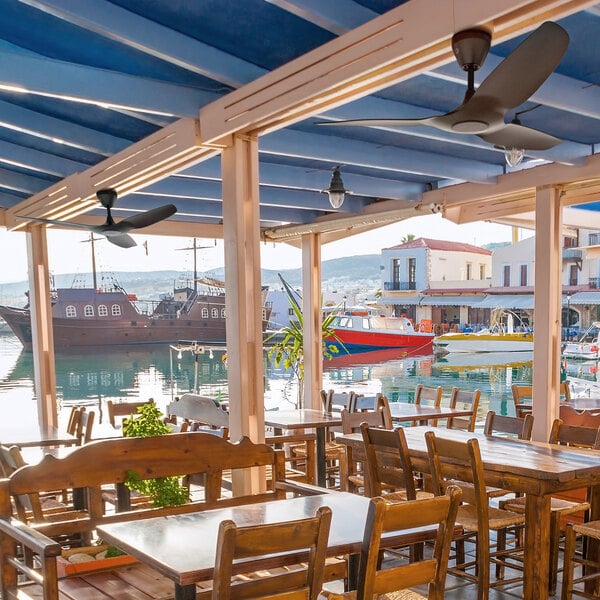 A black Haiku Coastal ceiling fan above a table and chairs in a restaurant.