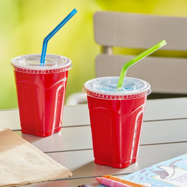 Two Solo red plastic cups with straws and lids on a table.