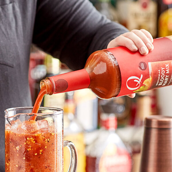 A person pours Q Mixers Premium Bloody Mary Mix into a glass.