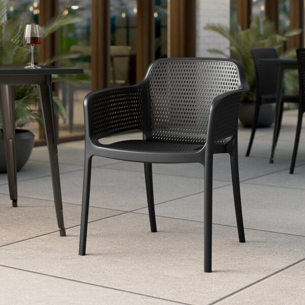 A black chair and table on an outdoor patio with a glass of wine.