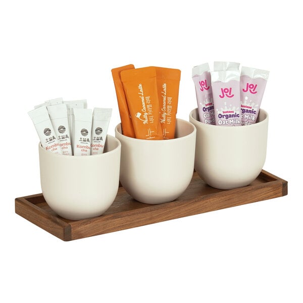 A Cal-Mil walnut condiment organizer with three white round cups inside.