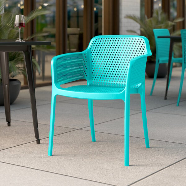 A Lancaster Table & Seating Rio Coastal Blue Resin Arm Chair sits on an outdoor patio.