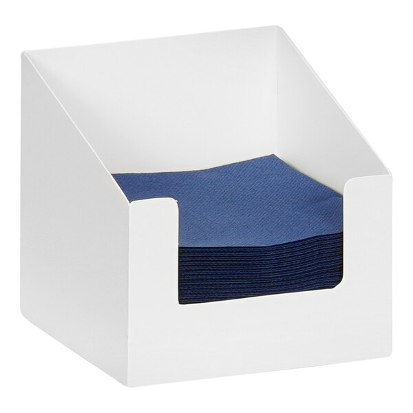 A white metal beverage napkin holder with blue napkins in it.