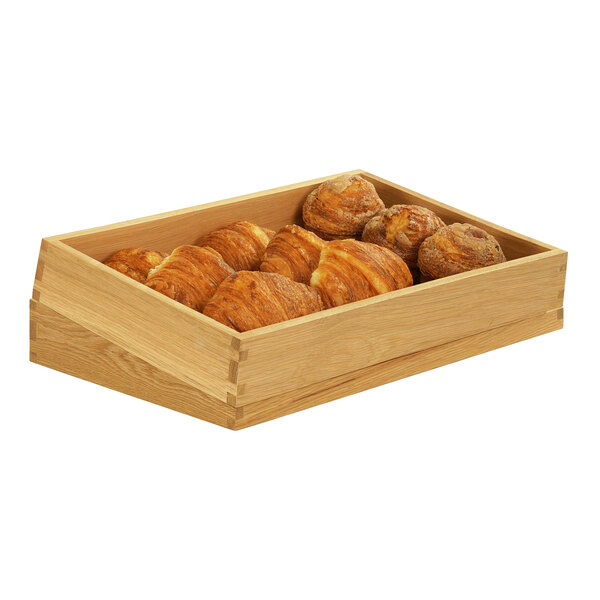 A Cal-Mil oak display box of pastries on a table in a bakery.