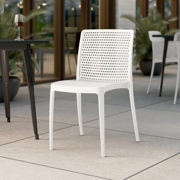 A Lancaster Table & Seating Rio Cloud White resin side chair on a tile floor.