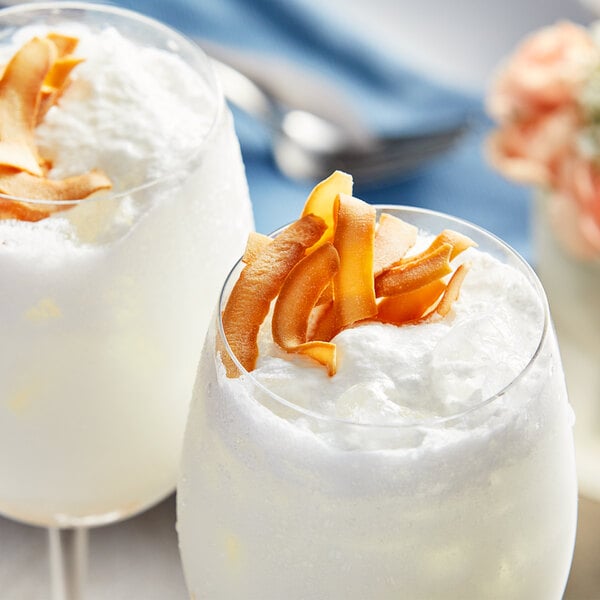 A glass of white liquid with coconut and orange peels on top.