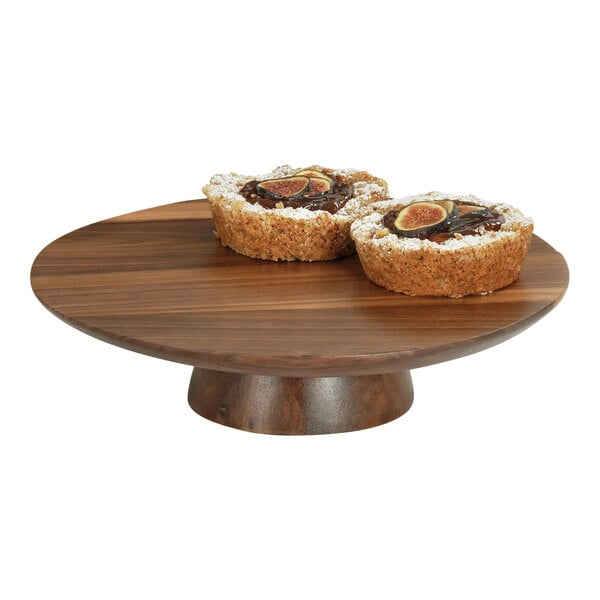 A round wooden Cal-Mil cake stand with two pieces of cake on it.