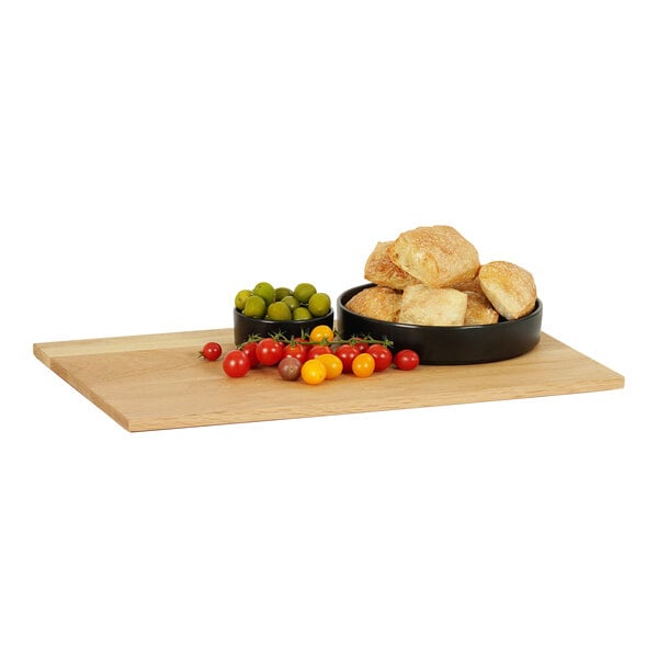 A Cal-Mil oak rectangular serving board with bread and cherry tomatoes in a bowl.