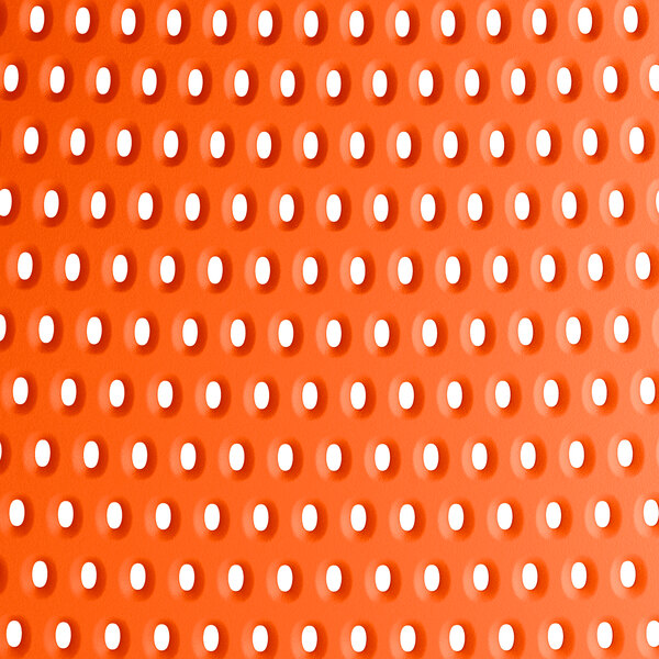 A close up of the perforated orange resin surface of a Lancaster Table & Seating Rio Sunset Orange side chair.