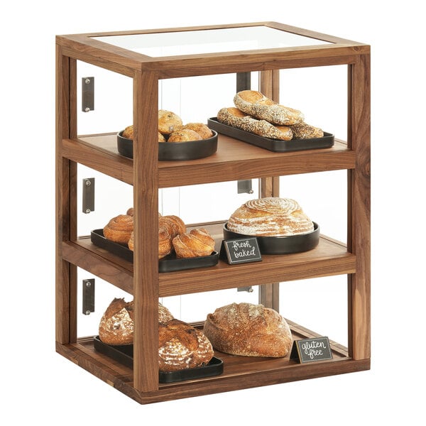 A Cal-Mil walnut bakery display case filled with pastries on a table.