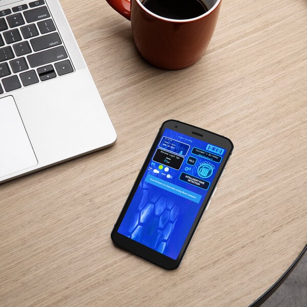 A Minor Decliner Smart Mobile-C ID Scanner on a table next to a laptop and a cup of coffee.