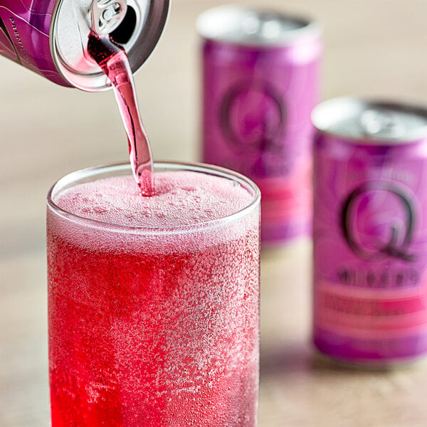 A Q Mixers Hibiscus Ginger Beer can pouring a pink beverage into a glass.