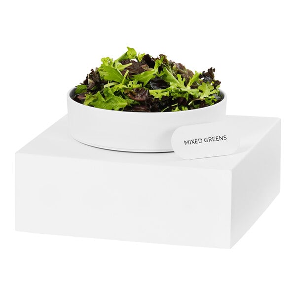 A white metal cube display stand holding a bowl of salad.