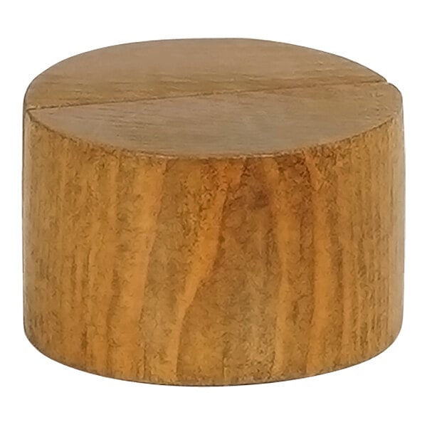 A brown wooden round card holder with a cross cut in it.