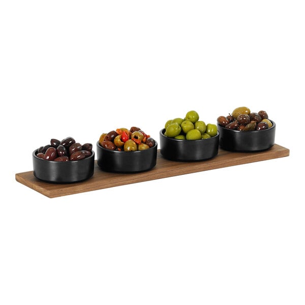 A Cal-Mil walnut rectangular serving board with bowls of green and black olives on a wood surface.