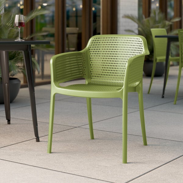 A Lancaster Table & Seating Rio Sea Moss Green resin arm chair on an outdoor patio.