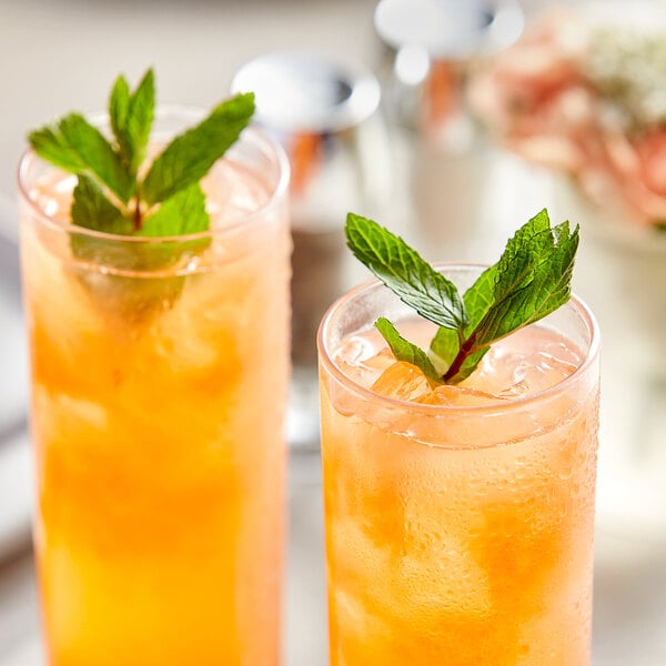 Two glasses of pink guava juice with mint leaves on top.