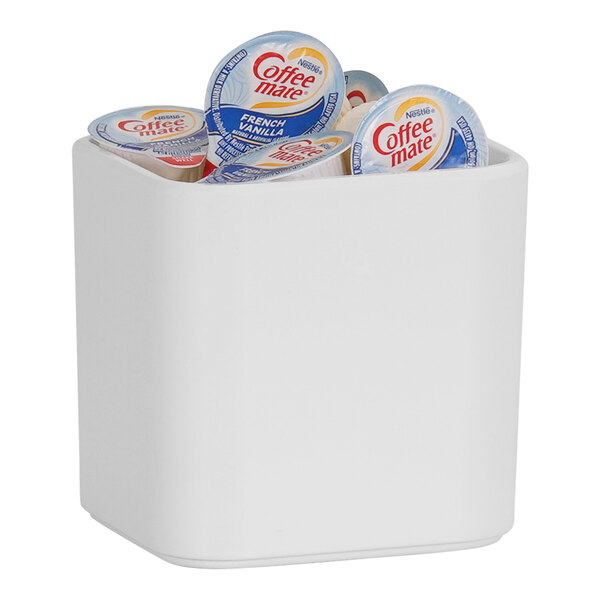 A white Cal-Mil crock with a group of creamer containers inside.