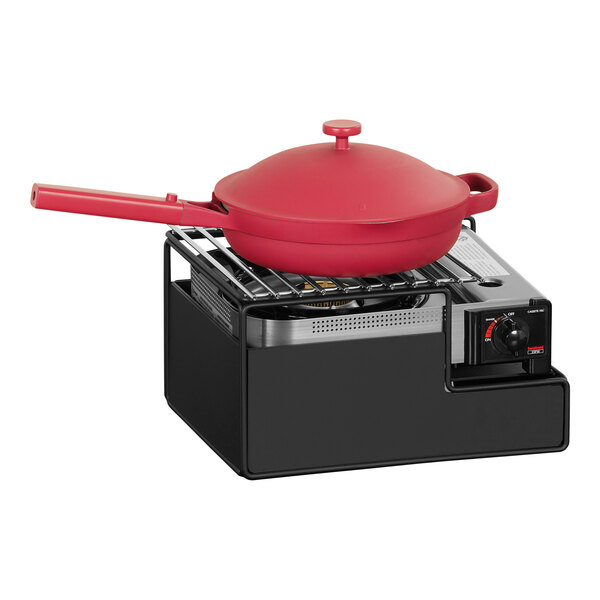 A red pot on a black metal butane stove frame.
