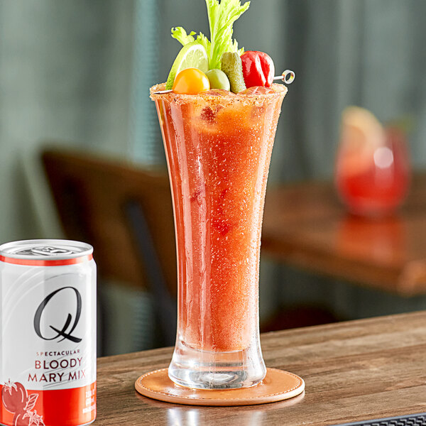 A glass of a red drink sits next to a white Q Mixers Bloody Mary mix can.
