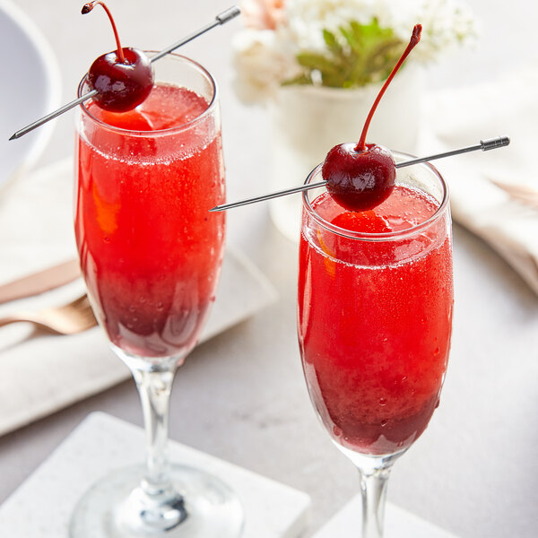 Two glasses of cherry cocktails with cherries on top.