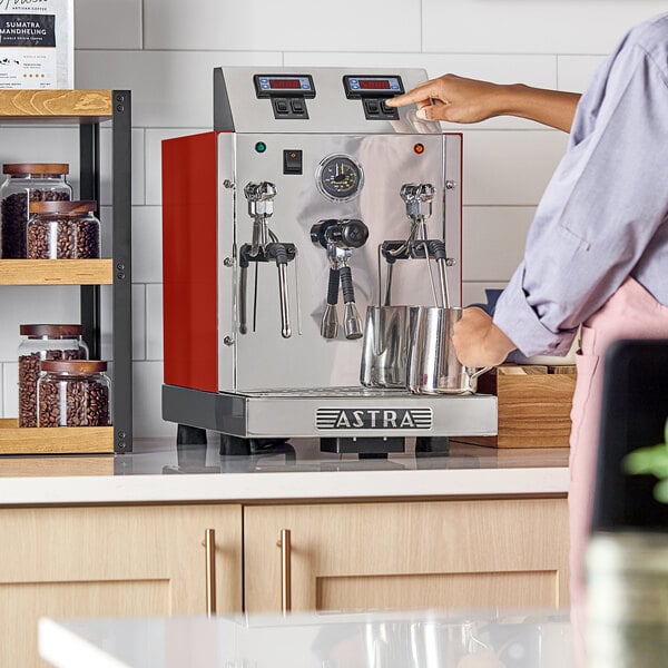 An Astra STA4800-RD gloss red automatic milk and beverage steamer with two wands on a countertop.