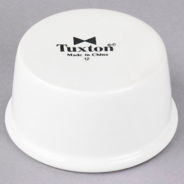 A white Tuxton china ramekin with black text.