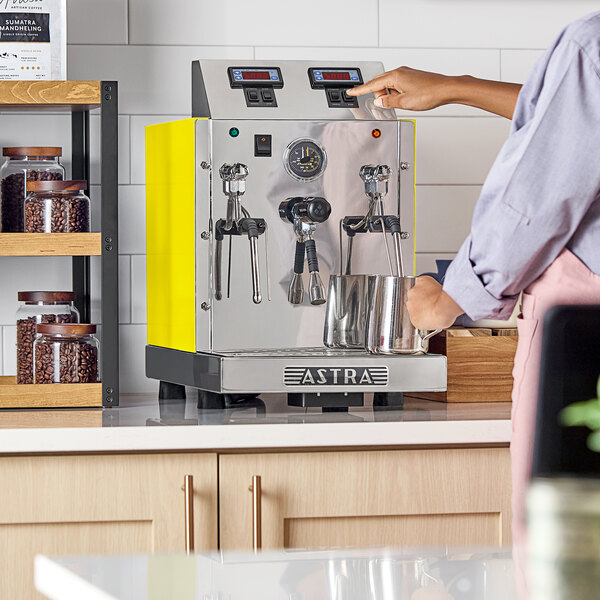 An Astra STA4800-YL gloss yellow automatic milk and beverage steamer with two wands on a countertop.