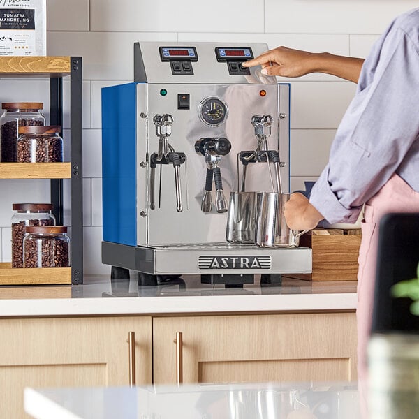An Astra STA4800-BL gloss blue automatic milk and beverage steamer with two wands on a countertop.