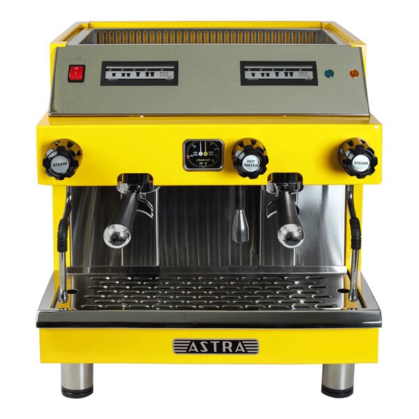 A yellow and silver Astra Mega II automatic espresso machine with two coffee cups on it.