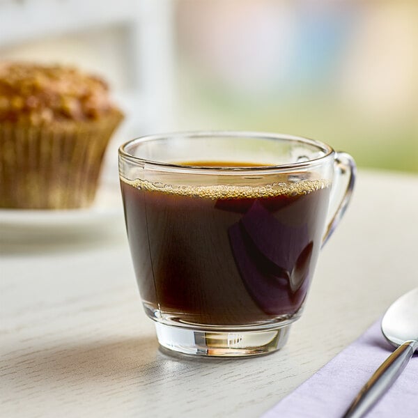 A glass of Pilon espresso on a table with a muffin.