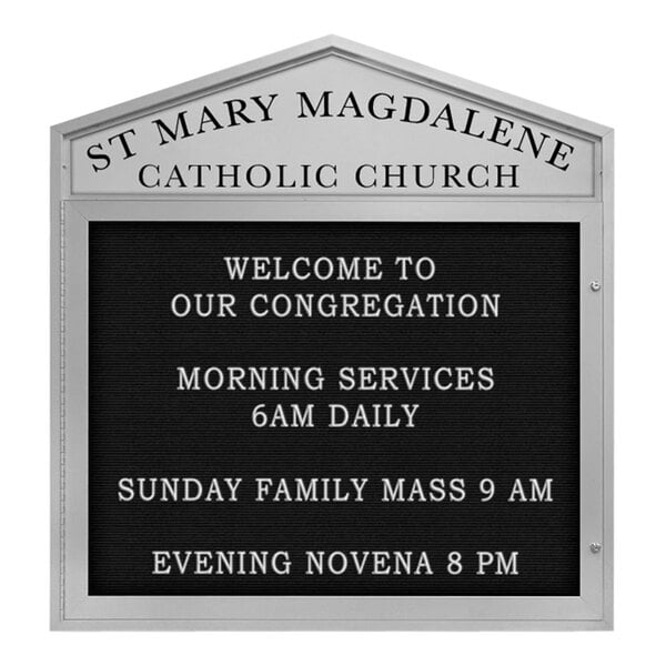 A white satin sign with black cathedral lettering that says "St. Mary Magdalene Catholic Church" in black.