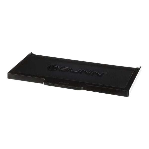 A black rectangular plastic lid with text.