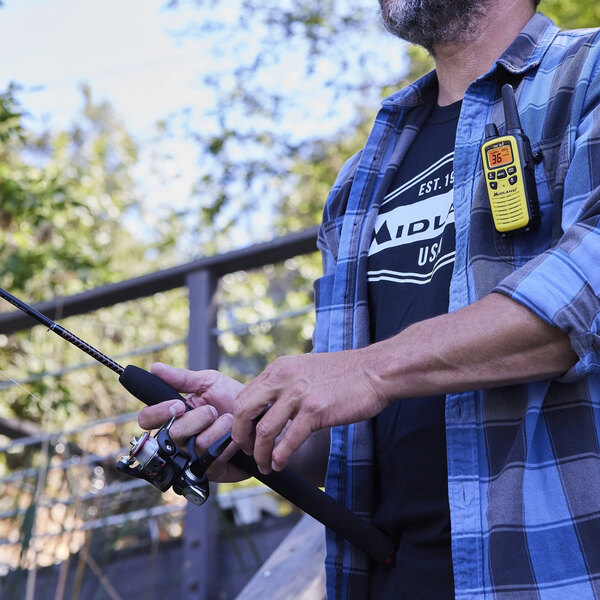 A man holding a Midland Yellow FRS walkie talkie while fishing.