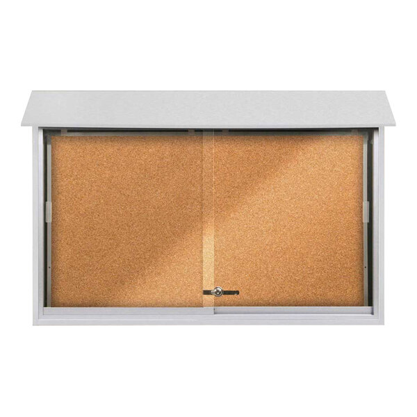 A white United Visual Products sliding glass door message center with corkboard inside.