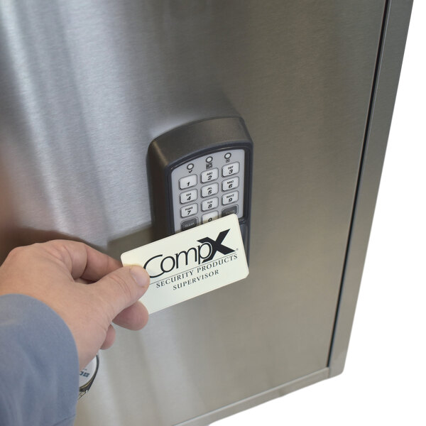 A person holding a card to a stainless steel cabinet with a keypad lock.