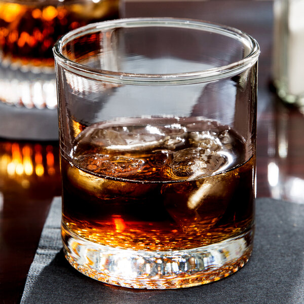 An Anchor Hocking room tumbler filled with whiskey and ice on a table.