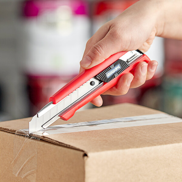 A hand using an Allway Tools Soft-Grip Snap-Off Knife to cut a box.