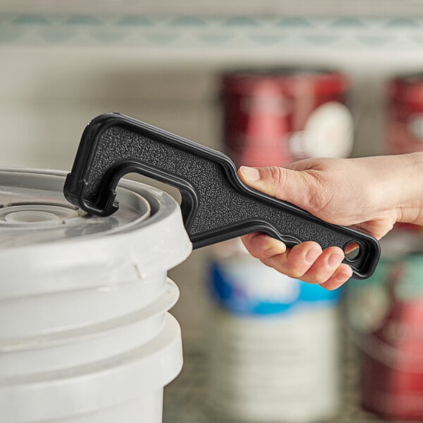 A hand with a black Allway Tools Plastic Pail Opener opening a white pail.