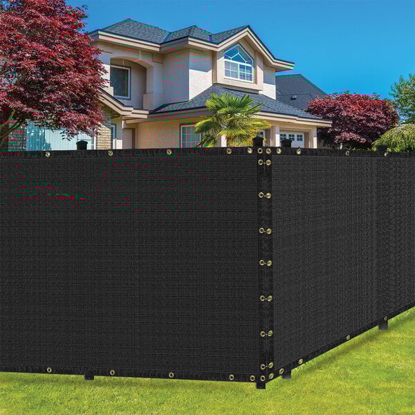 A black SEALTECH fabric privacy fence screen in front of a house.