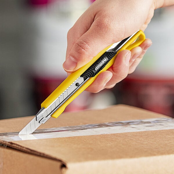 A hand uses a yellow Allway Tools snap-off knife to cut a box.