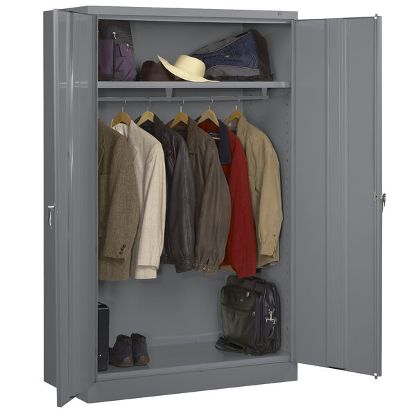 A dark gray metal Tennsco wardrobe cabinet with clothes and bags.
