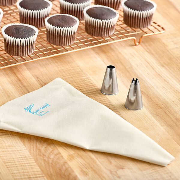 A chocolate cupcake with white frosting next to a pastry bag with metal tips.