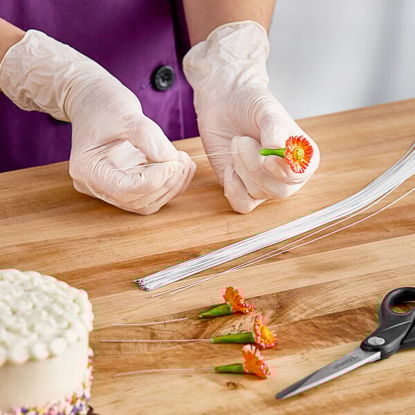 A person holding a white floral wire needle.