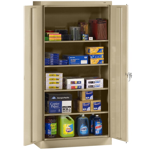 A Tennsco sand-colored metal storage cabinet with solid doors and many items on it.