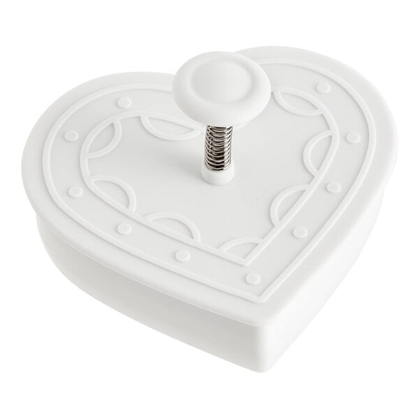 A white heart-shaped plastic cutter with a metal spring.