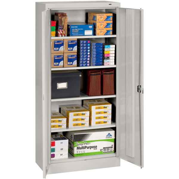 A Tennsco light gray metal storage cabinet with solid doors and many shelves filled with boxes.