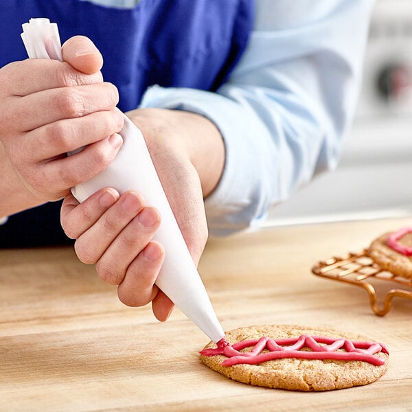 A hand using an Ateco Flex polyurethane-coated pastry bag to decorate a cookie.